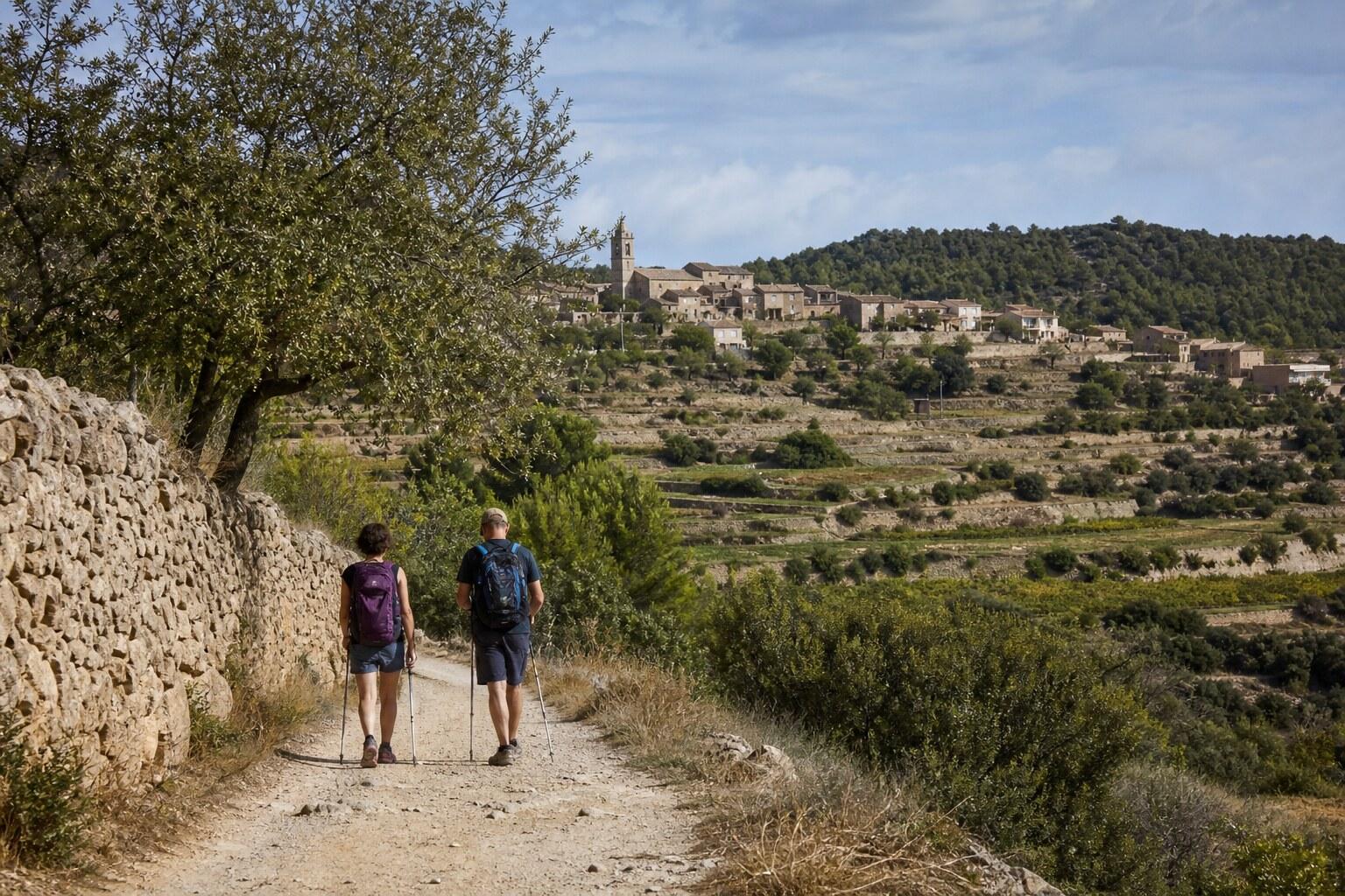 Hikers crossing dry Mediterranean countryside between stone villages